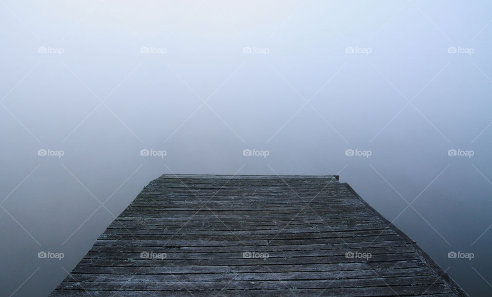 wooden pier at the foggy lake in polish countryside