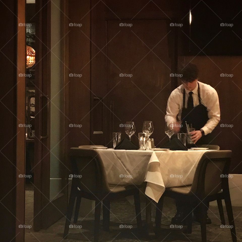 Waiter at Kirby’s Steak House is setting up a table for fine dining and cocktails 🍹