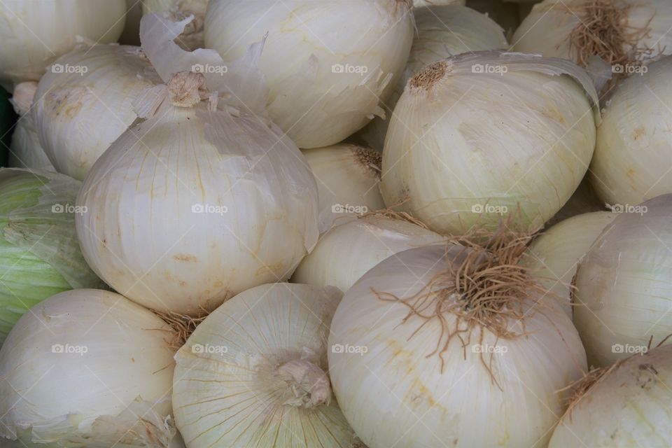 A heap of raw white onions for sale outside a market in Brooklyn, New York City.