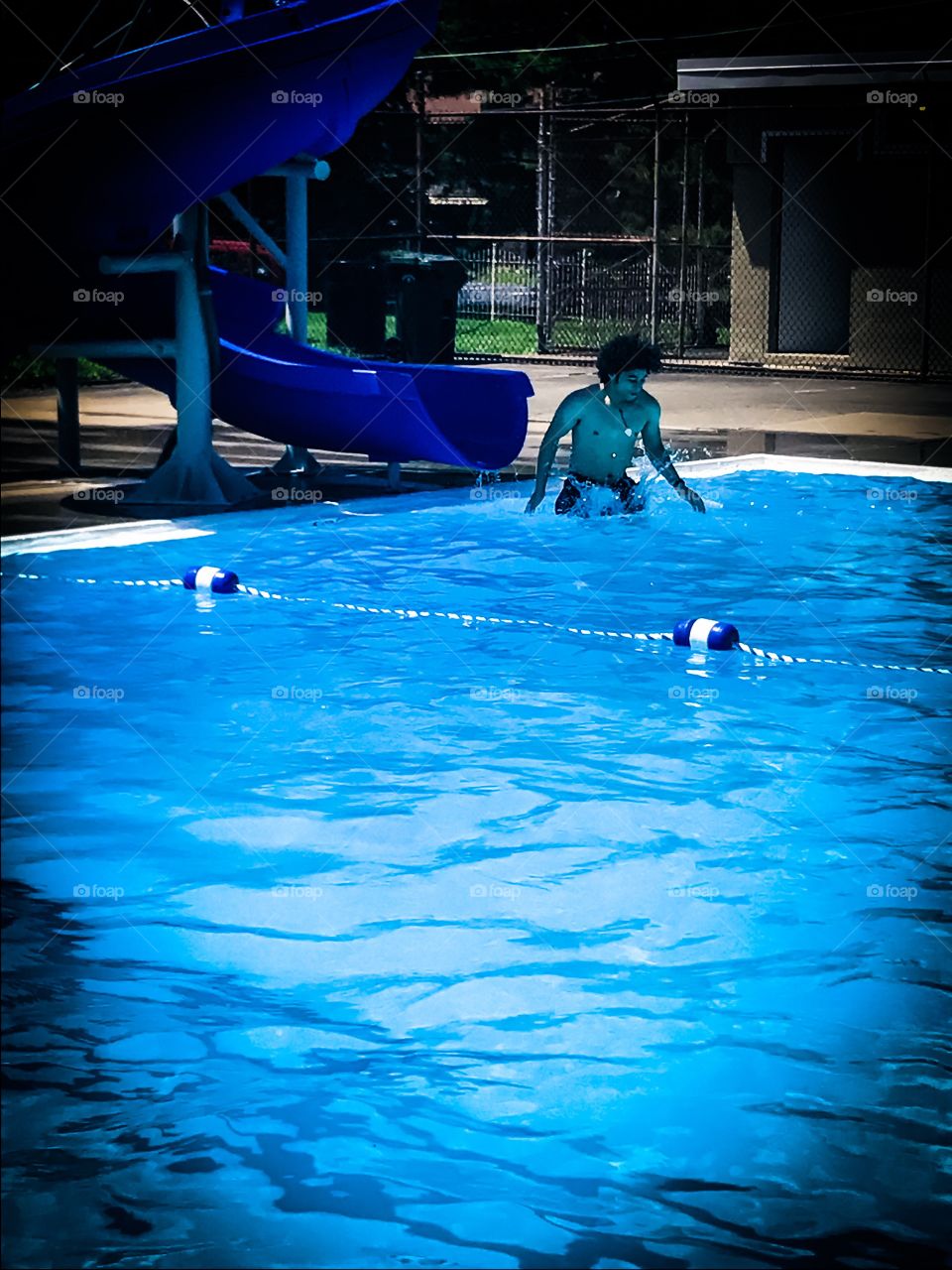 Young man going off water slide into pool.