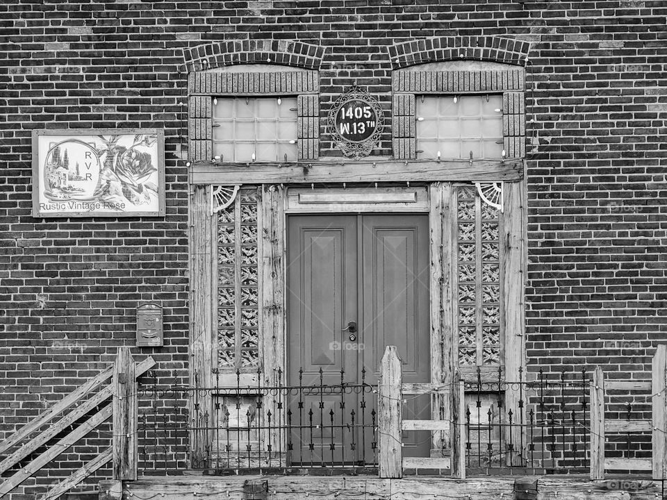 A black and white representation of an interesting doorway leading into an old building that appears to be gaining a second life