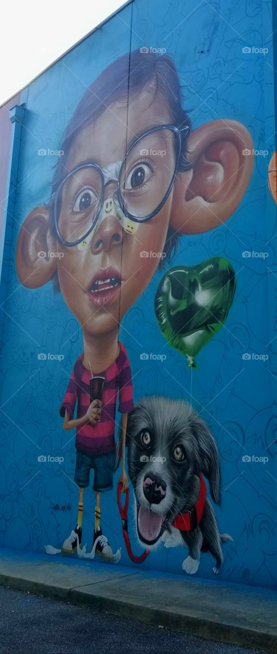 Fun boy and his dog mural on side of building great colors.