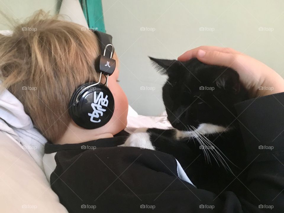 Cat takes a nap on boy with head phones