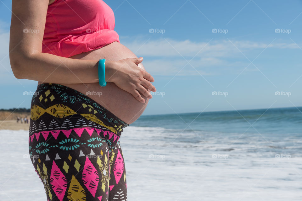 Pregnant woman in bright cloths holding her belly