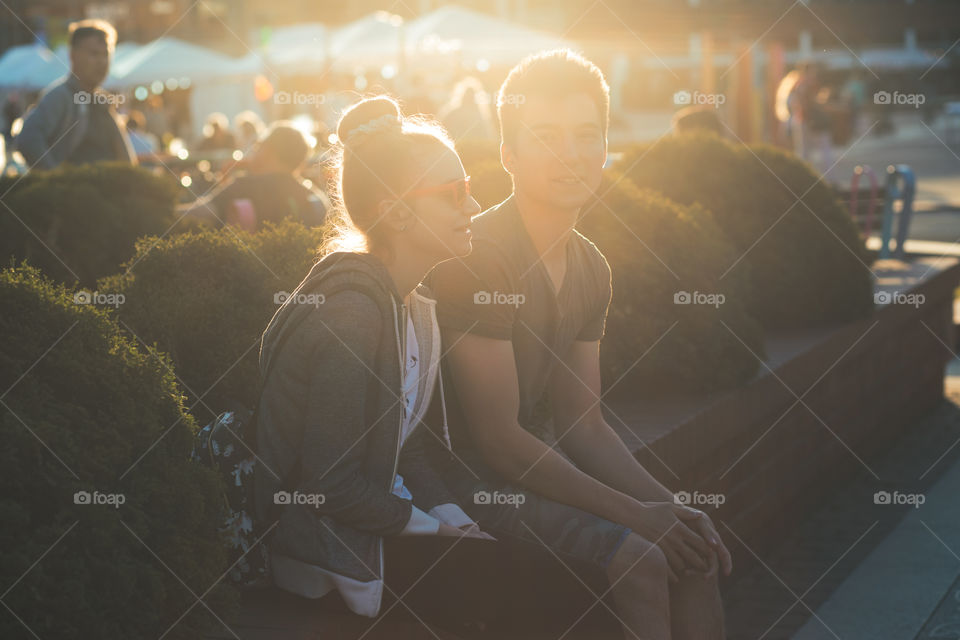 Couple of friends, teenage girl and boy,  having fun together, sitting in center of town, spending time together