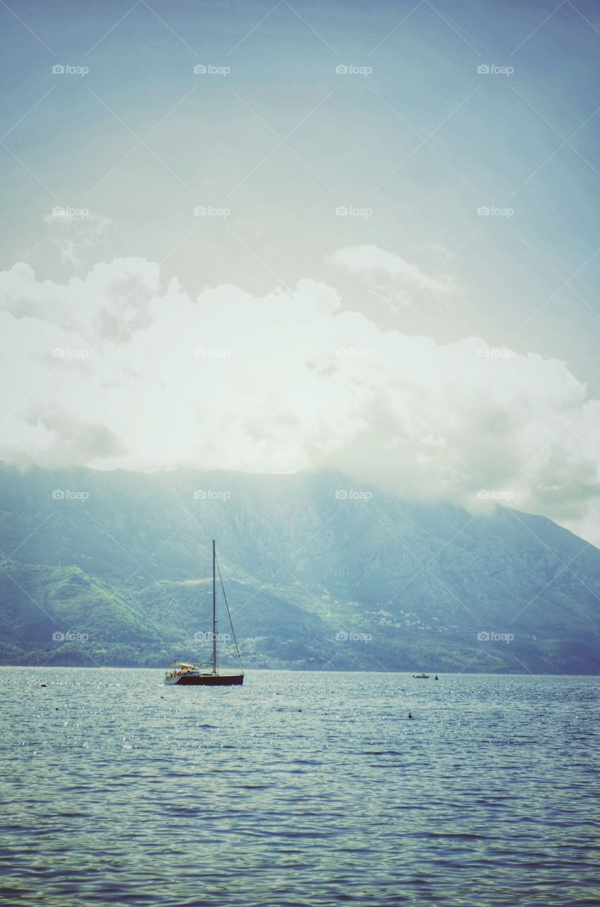 A boat sailing on the open sea. Peaceful. Summer holidays at the seaside. The sea and the mountains.