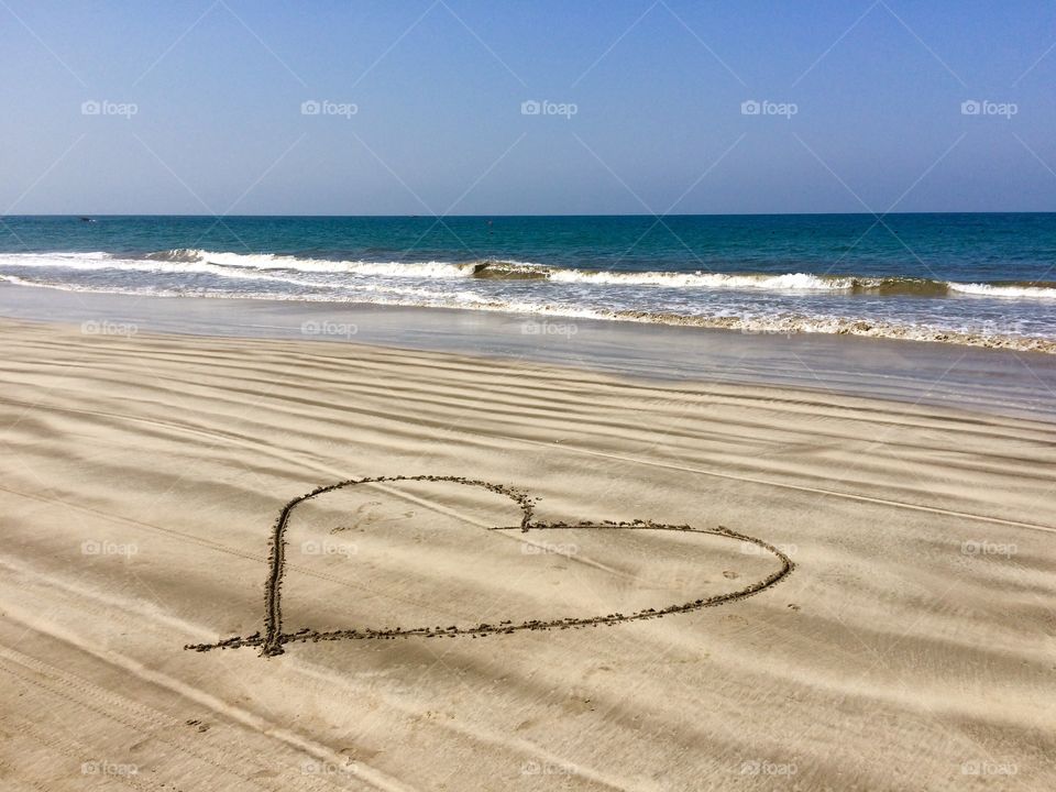Heart shaped drawing on sandy beach
