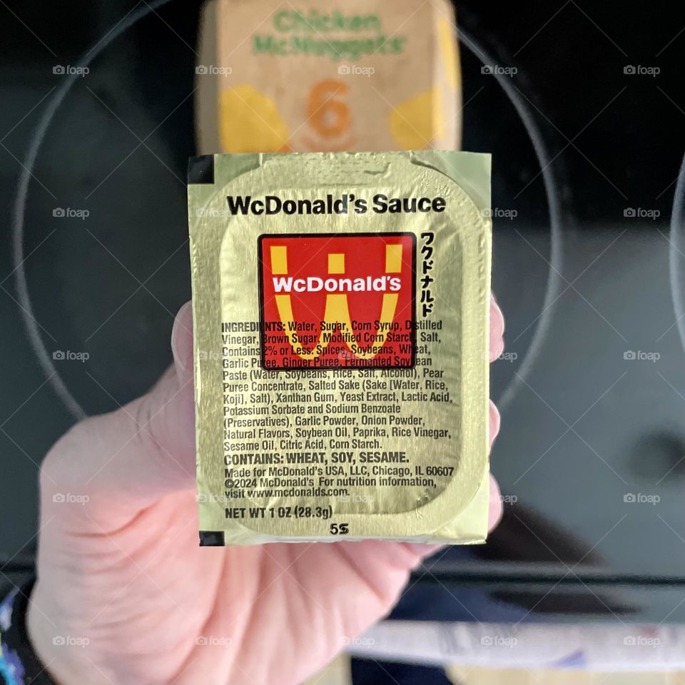 Trying new McDonald’s sauce for the first time, eating McDonald’s chicken nuggets, holding new McDonald’s sauce, woman’s hand holding new McDonald’s Sauce, first person perspective