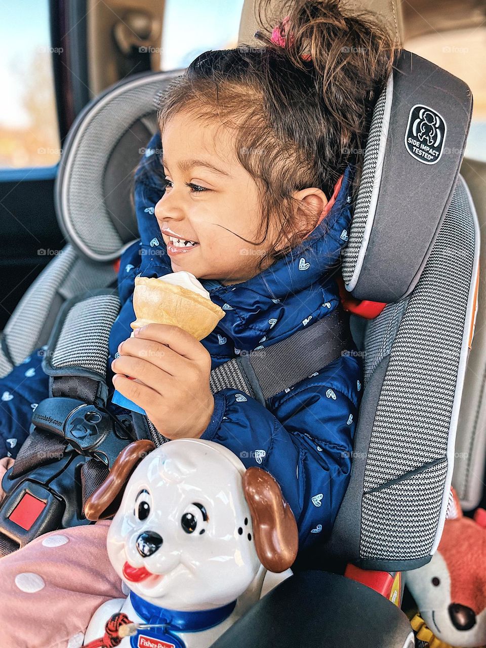 Toddler girl with ice cream and toy puppy dog, toddler eats ice cream cone in the car, toddler girl in car seat eating ice cream, delicious treats at the local Dairy Queen, eating dessert before dinner, puppy dog toy rides with toddler to Dairy Queen