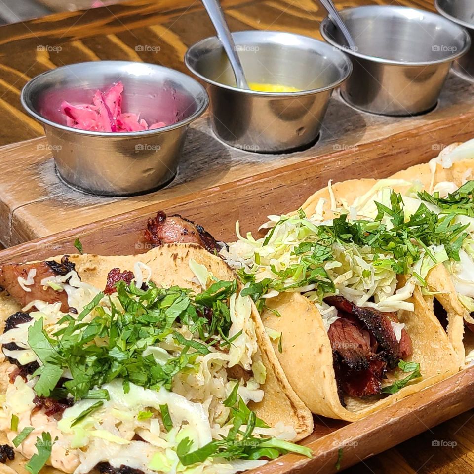 Variety of delicious meat tacos with condiments, Mexican food elevated to another level, topped with refreshing slaw