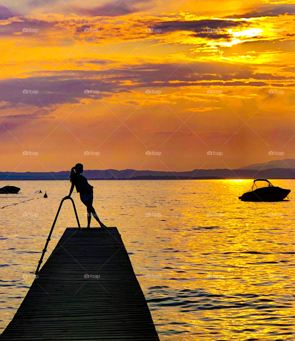 sunset by the Swiss lake, mountains, bridge, yacht, boat, man in the shadow, shore, romance, beautiful red sunset