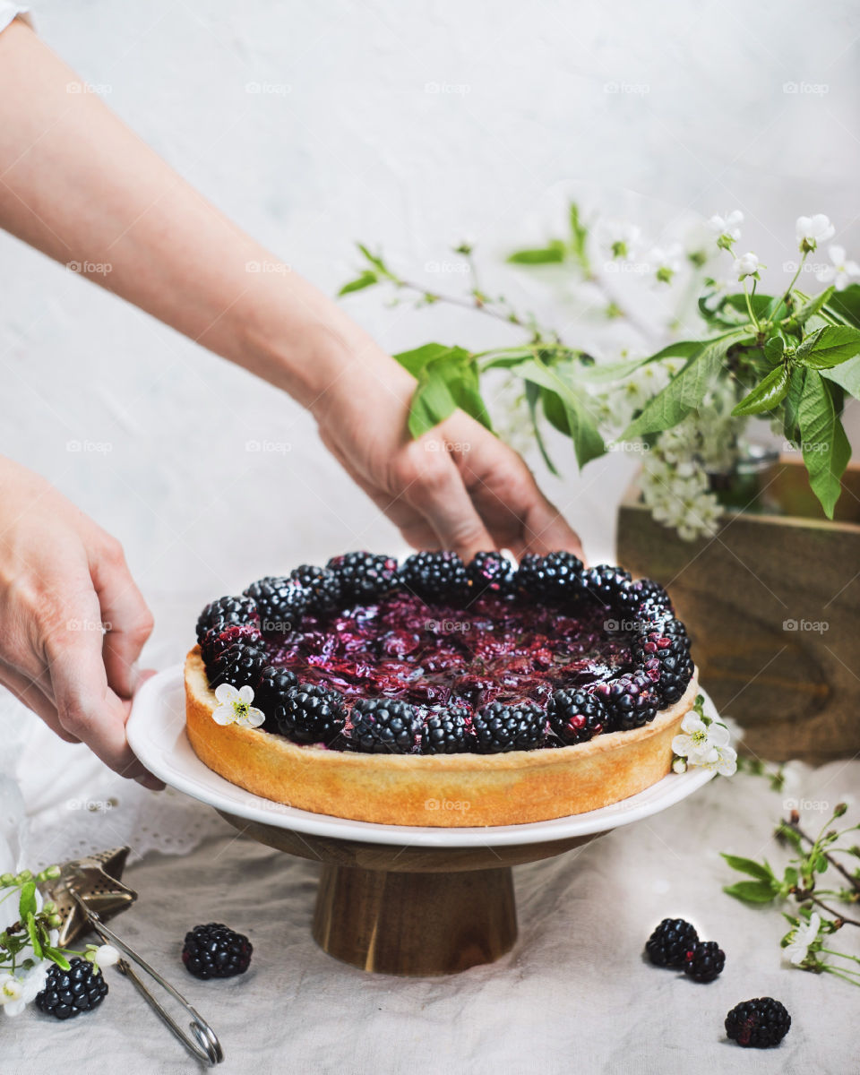 Female hands holding blackberries pie