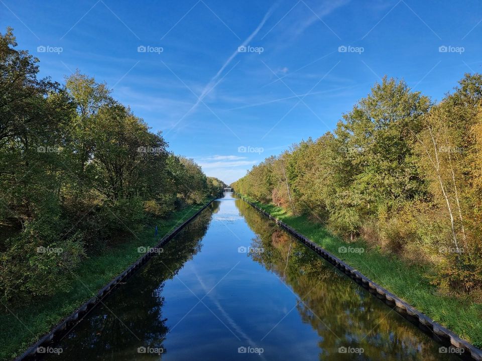 Water, sky & green (canal lined with green trees under a blue sky)