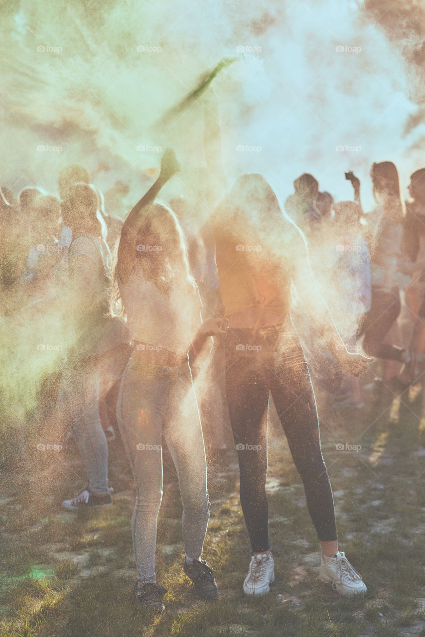Portrait of happy smiling young girls with colorful paints on faces and clothes. Two friends spending time on holi color festival. Real people, authentic situations