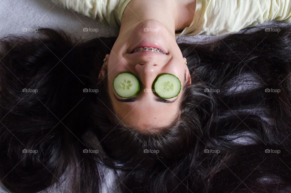 Funny Portrait of Girl with Slices of Cucumbers on Her Eyes