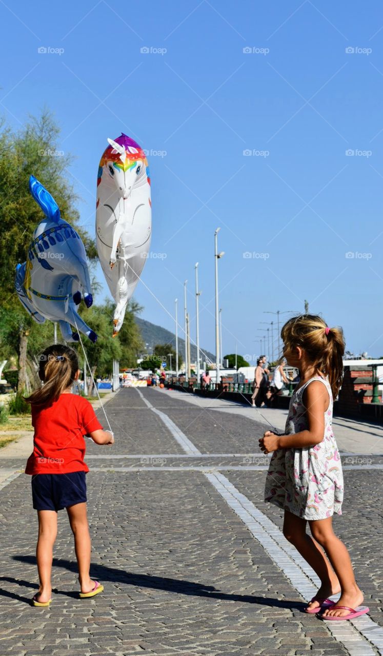 two little girls playing with unicorn balloons