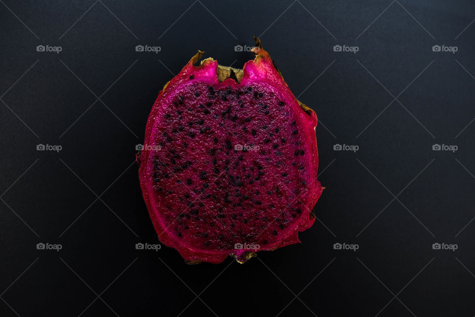 Dark image of an open dragon fruit against a black background