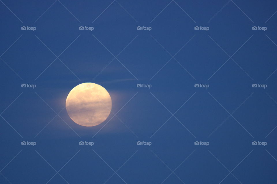 Full moon rising slowly on an almost perfect blue sky 