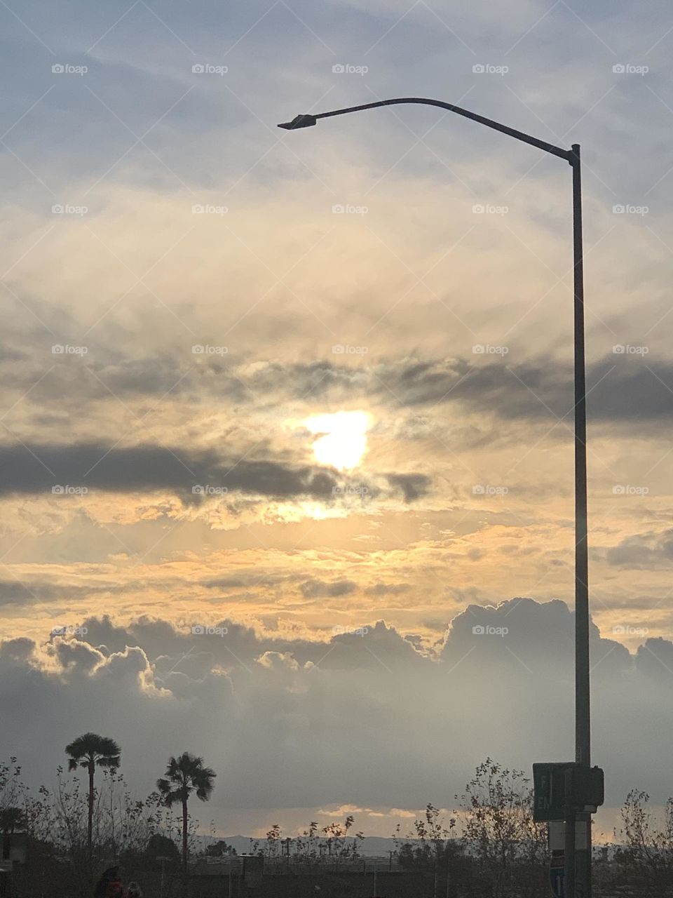 Clouds surround the sun as it prepares to set.