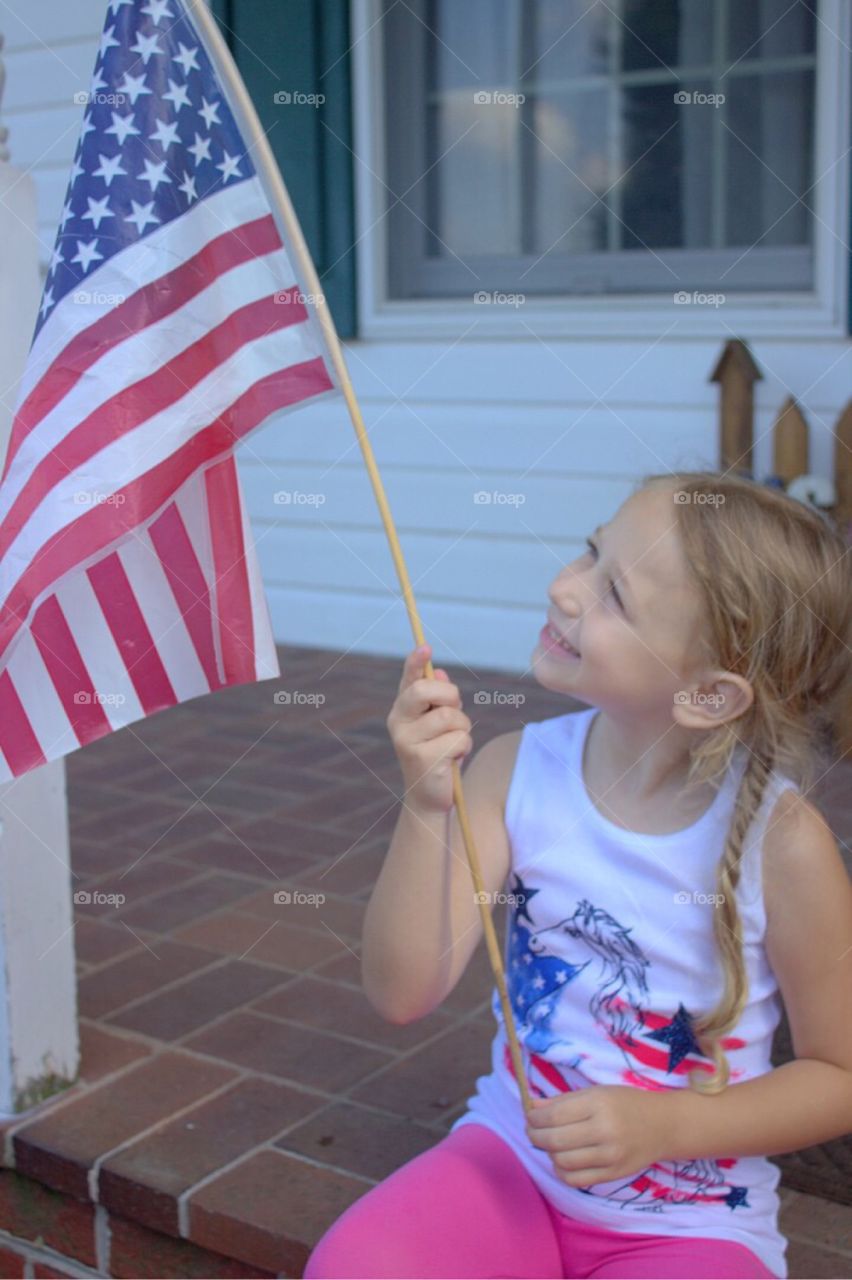 Sweet little girl smiling proudly at the American Flag. 