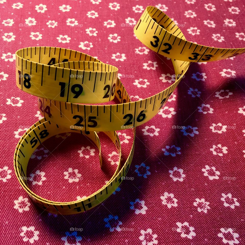 Measuring tape on vintage red fabric.