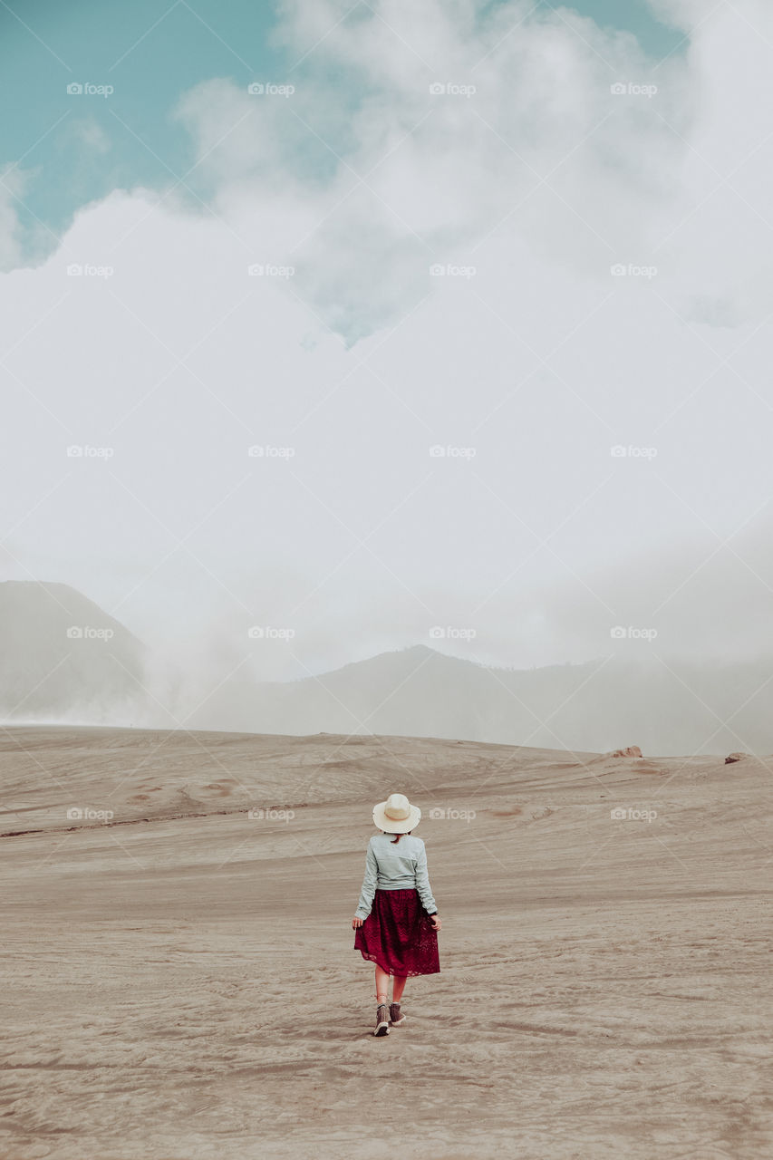 Rear view of woman walking on sandy land