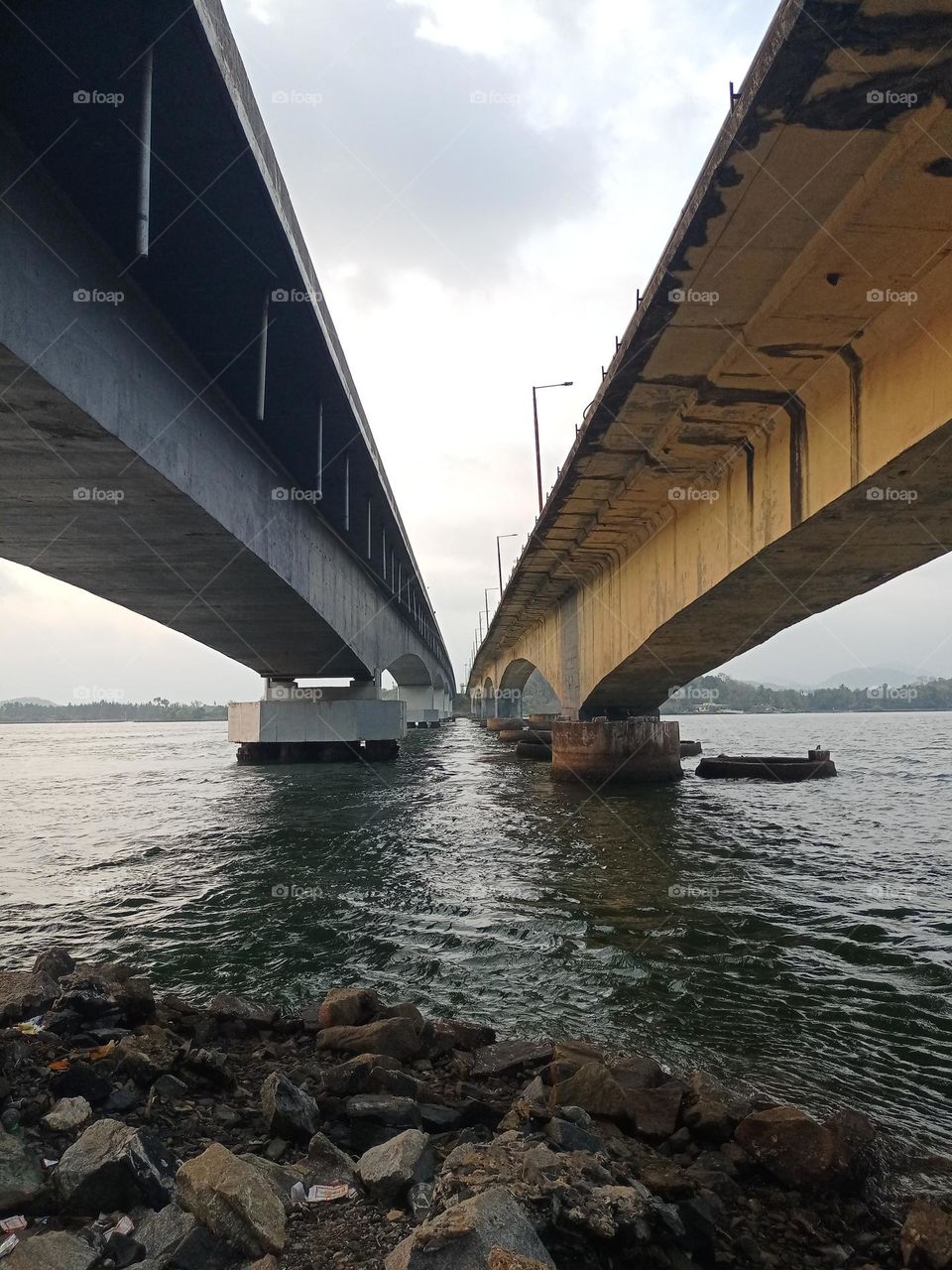 Beautiful view of under the twins bridges it's looking amazing with nice background of sky clouds water and landscape in sunset time