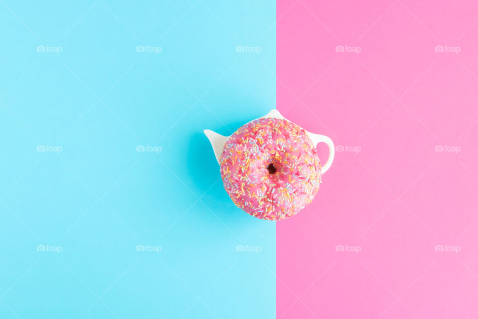 Top view to pink sweet donut on pink and blue background. Copy space.