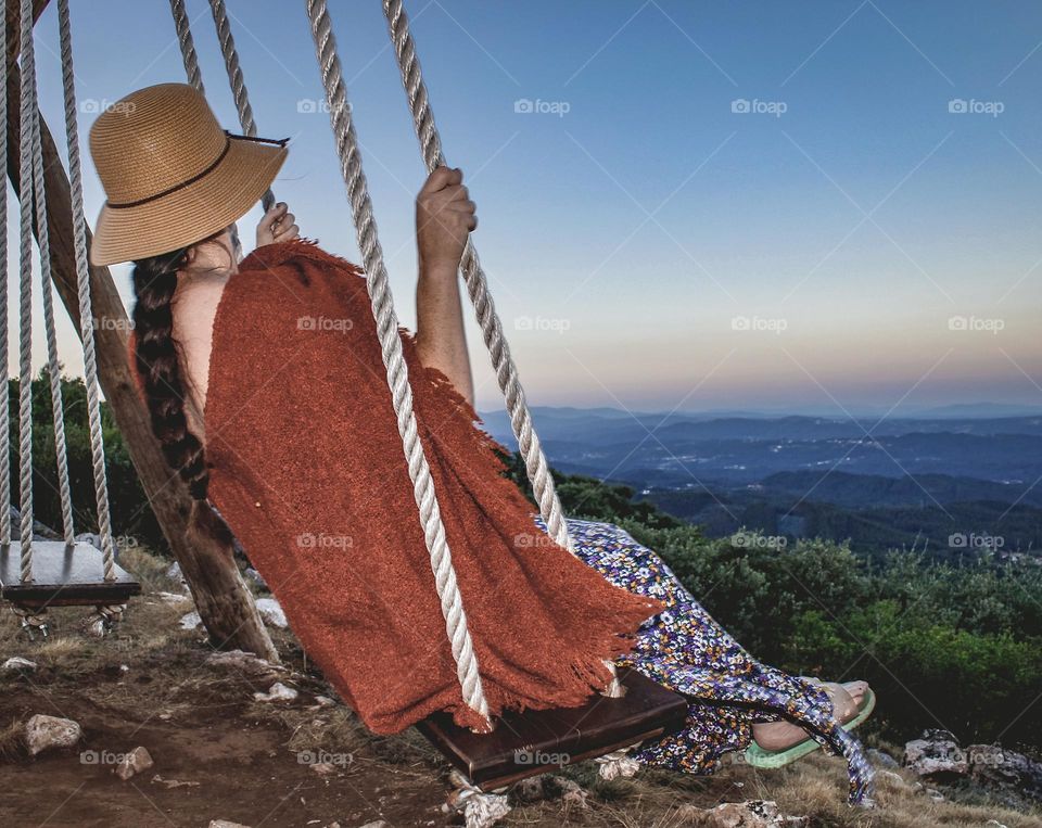 A woman on a swing overlooking the countryside around sunset