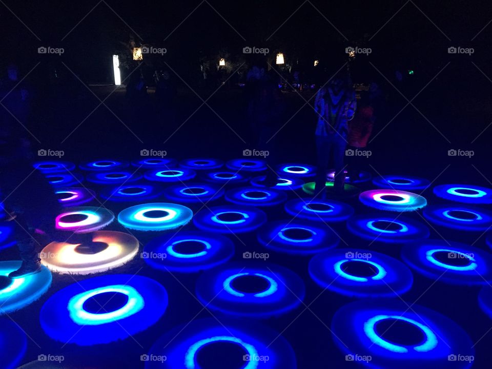 Glowing blue circles in a pattern on the ground. There are a few in other colors scattered among them. 