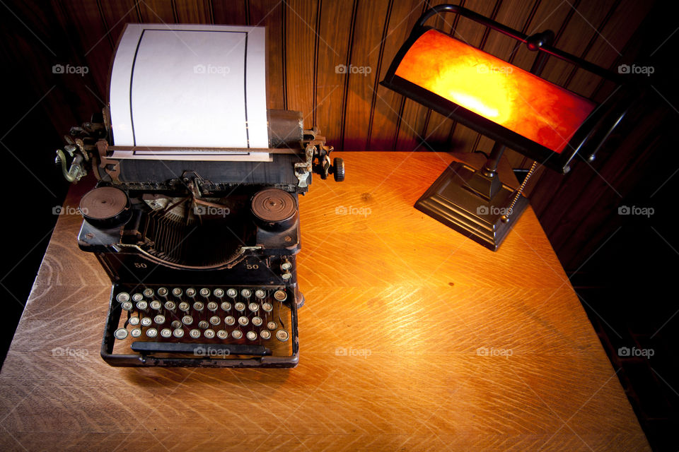 desk with old vintage typewriter and lamp . Wooden desk with vintage typewriter and yellow lamp white blank paper