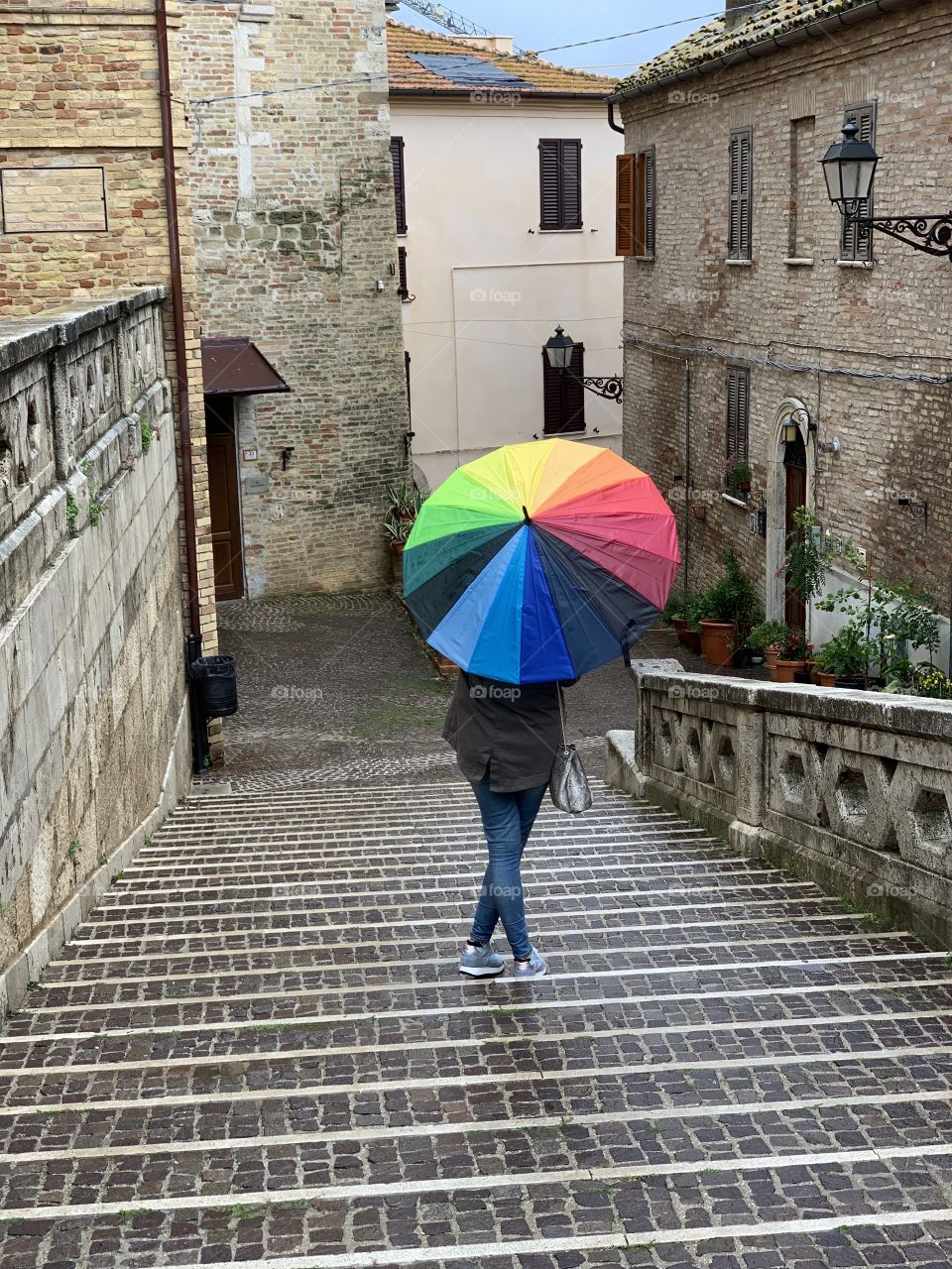 Discovering an old village during a rainy day with a rainbow colored umbrella