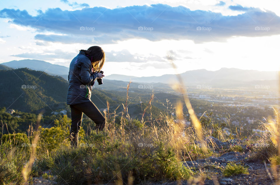 Young caucasian girl at the top of a mountain photographing beauty in nature