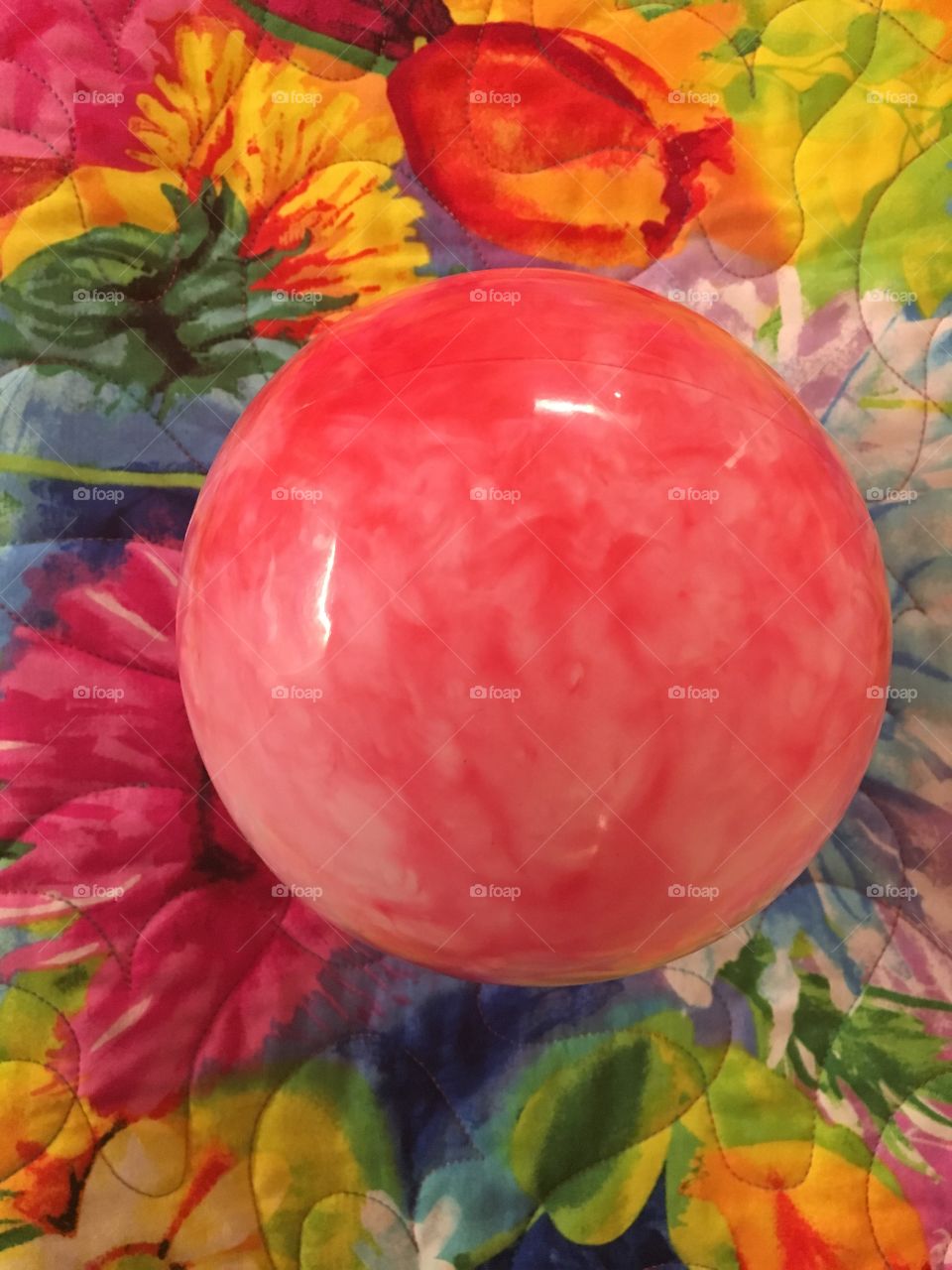 Pink mottled ball sits in a floral quilt