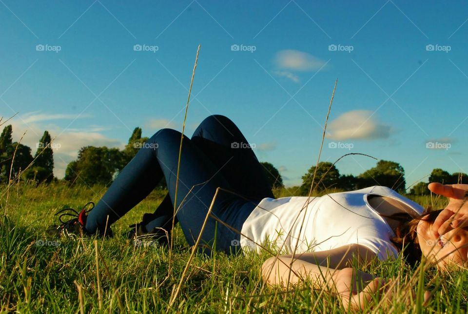girl laying on the fresh grass wearing sportswear smiling feeling happy in the lovely summer months