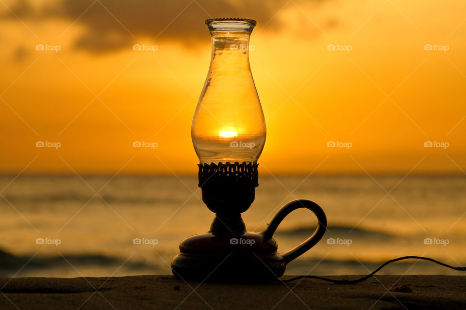 Close-up of a lighting equipment in front of sea at sunset