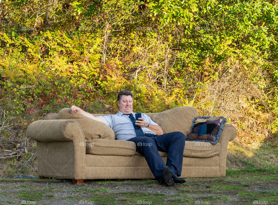 Businessman takes a relaxing break on a comfortable sofa in the middle of a peaceful forest