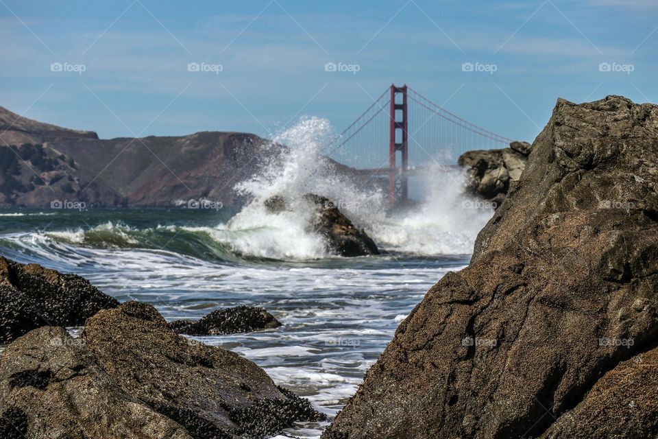 Waves crashing upon the rocks at Lands End Beach in San Francisco with the Golden Gate Bridge in the background 