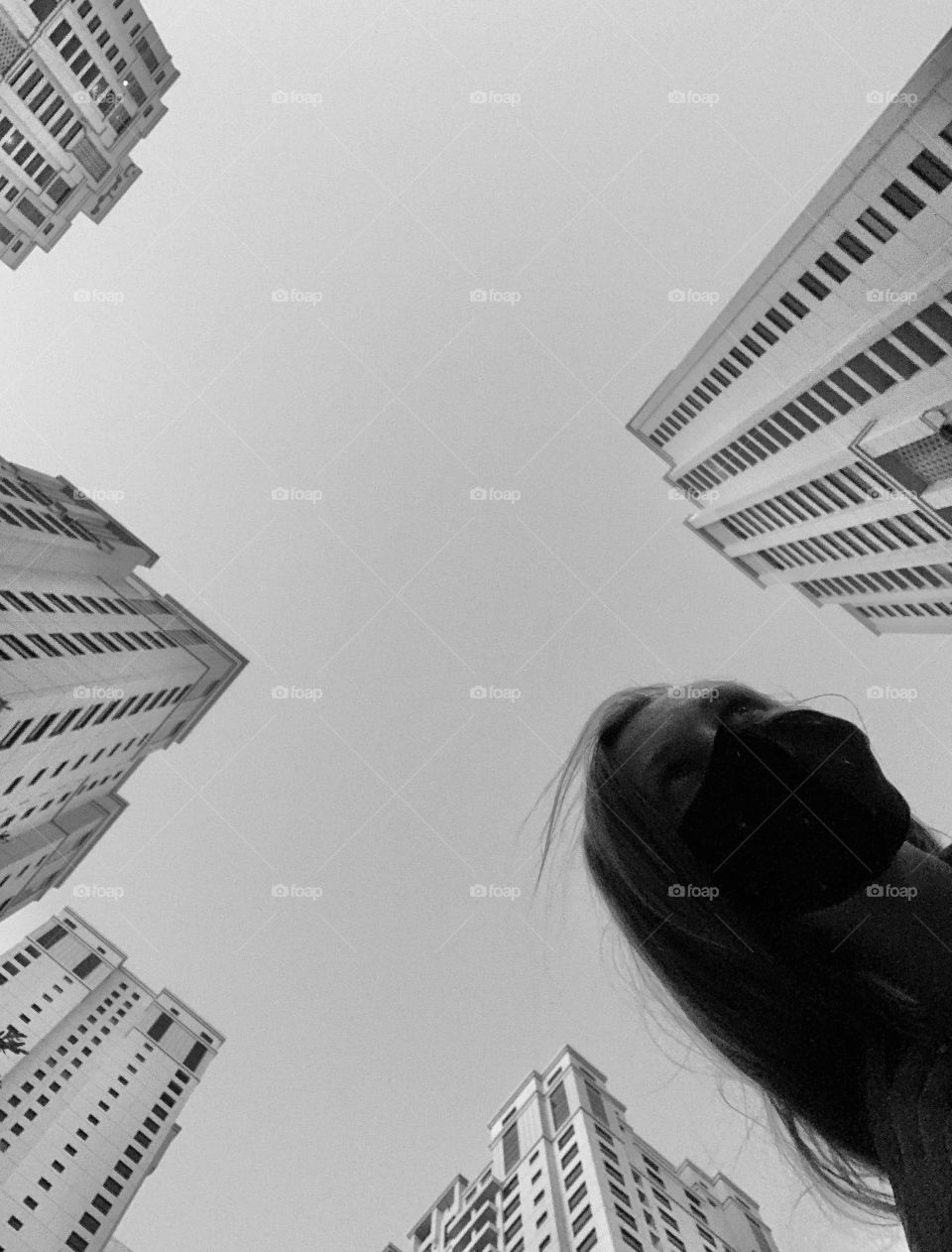 Low angle selfie in face mask between skyscrapers 