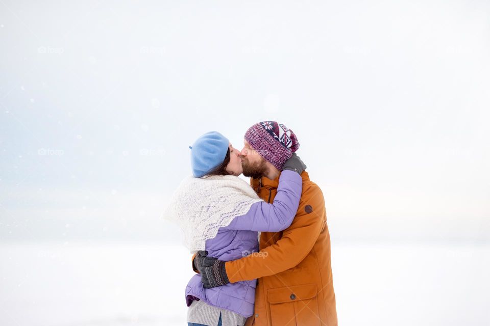 Happy married couple hugging and kissing outdoors in winter