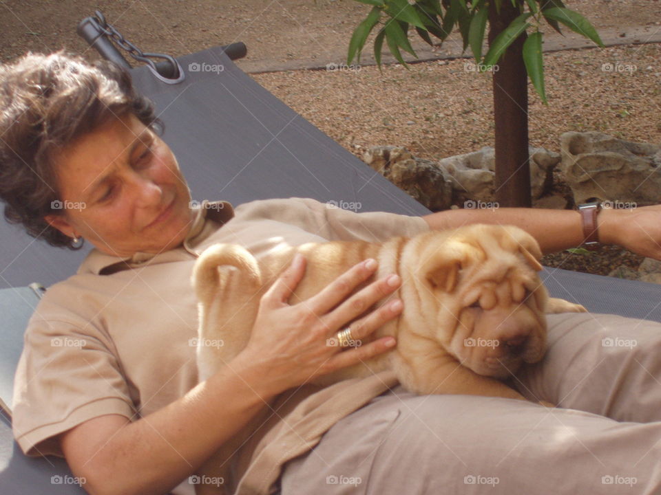 Female pet owner lying with brown puppy