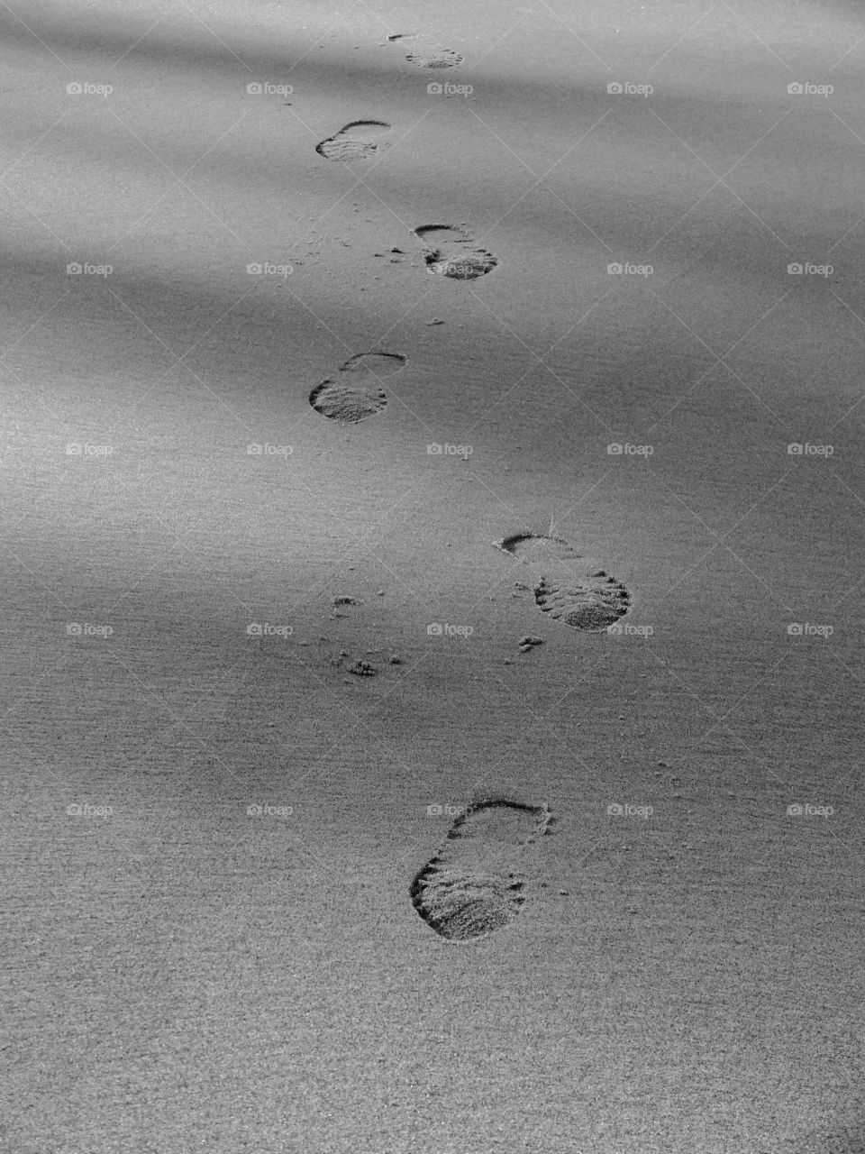 Black and white shot of footprints on the beach in Rewal, Poland.