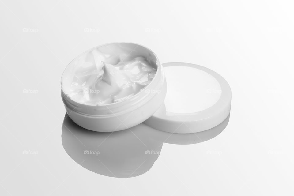 Blank white cream jar packaging on white reflective background