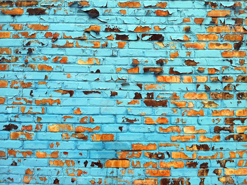 Chipping blue paint on a brick wall