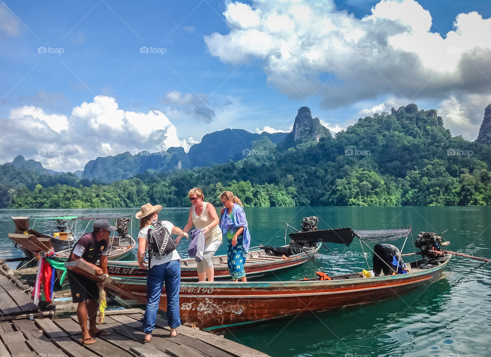 Traveling in Thailand. Tourists getting on long-tailed boat in Chiew Larn dam at Khoa Sok national park, Thailand.