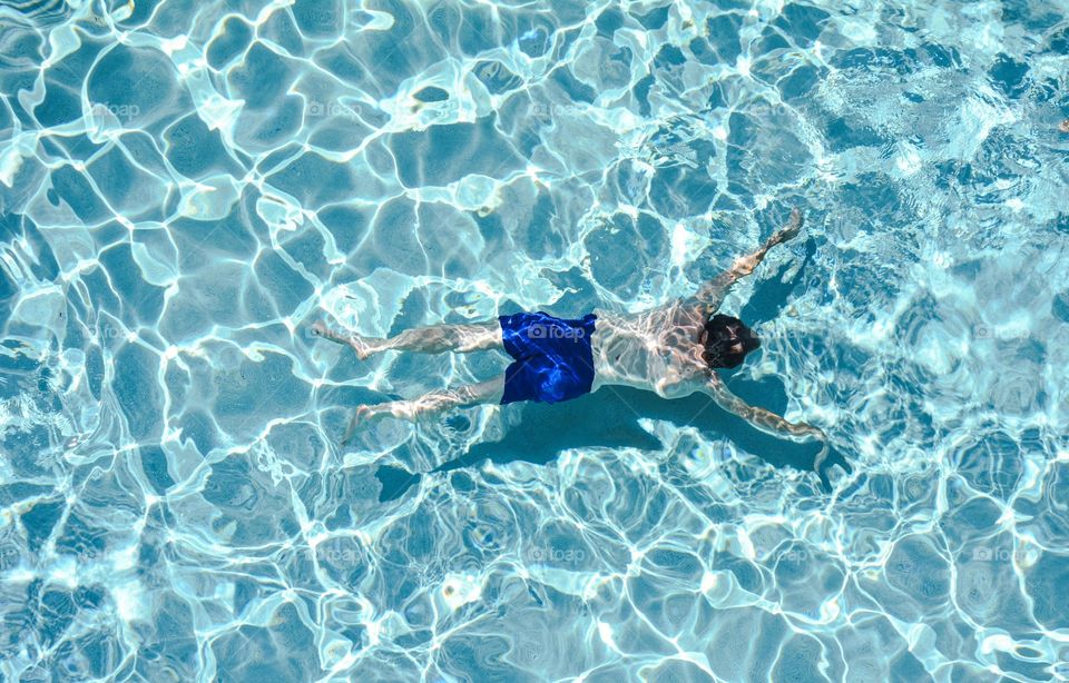 Man swimming under blue water in swimming pool