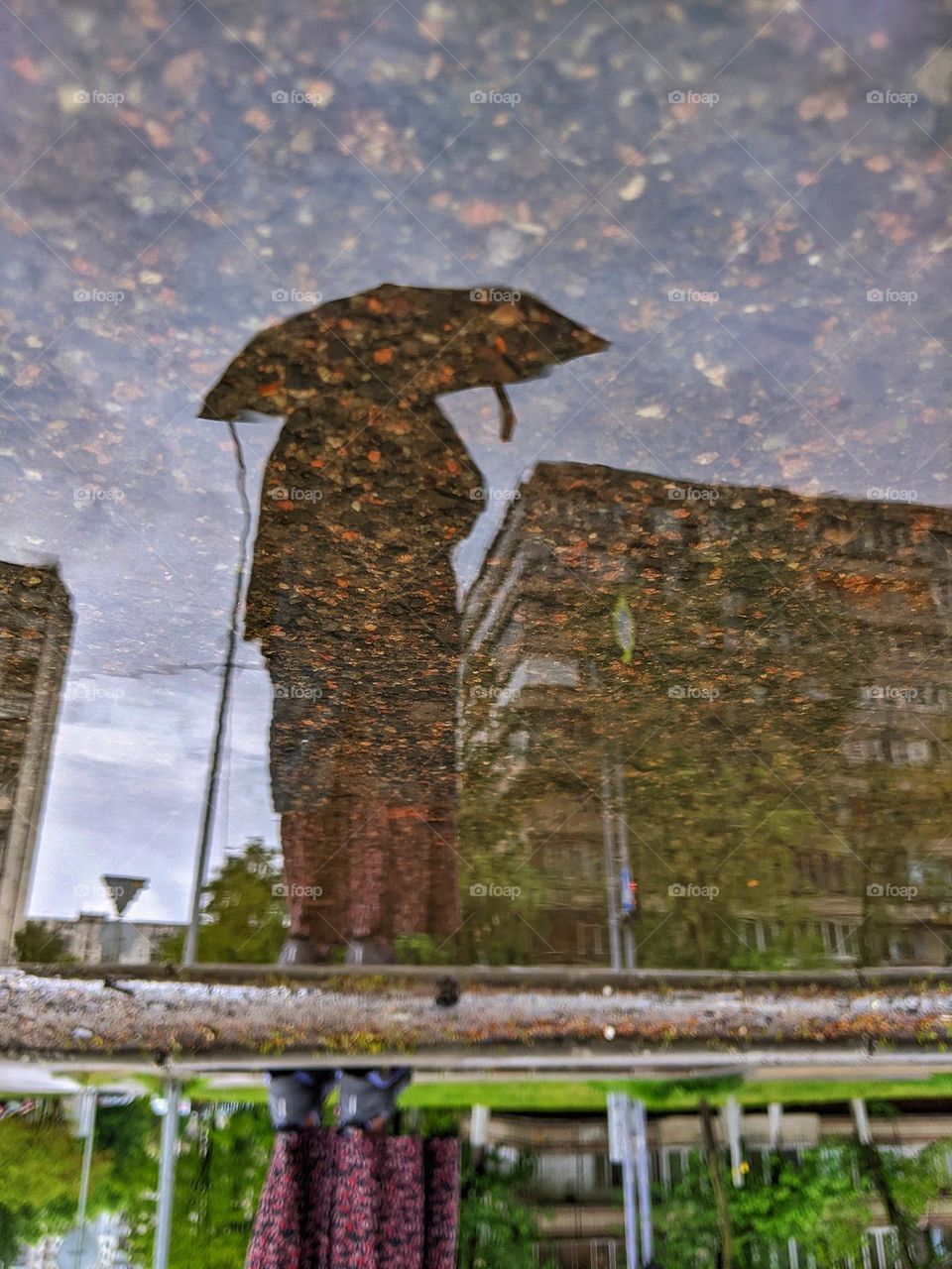 reflection in a rain puddle of a girl under an umbrella