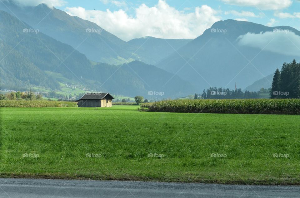 Small house on green field with mountains background . Small house on green field with mountains background Germany 