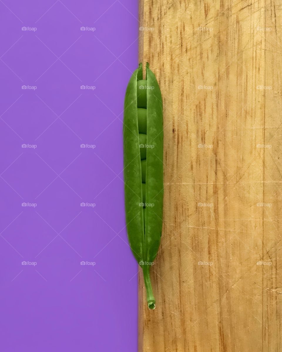 A green pea on wooden background and violet background 