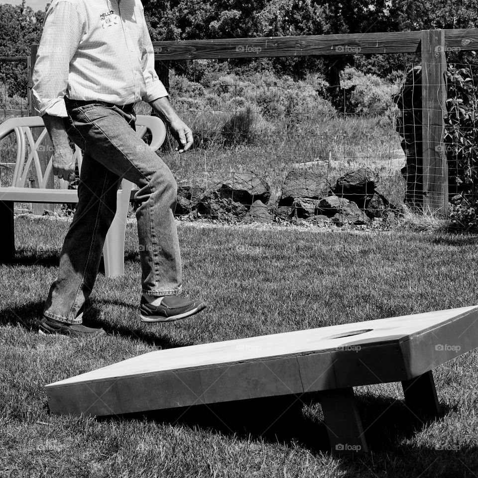 A participant in a bean bag toss game measures the distance between targets in steps. 